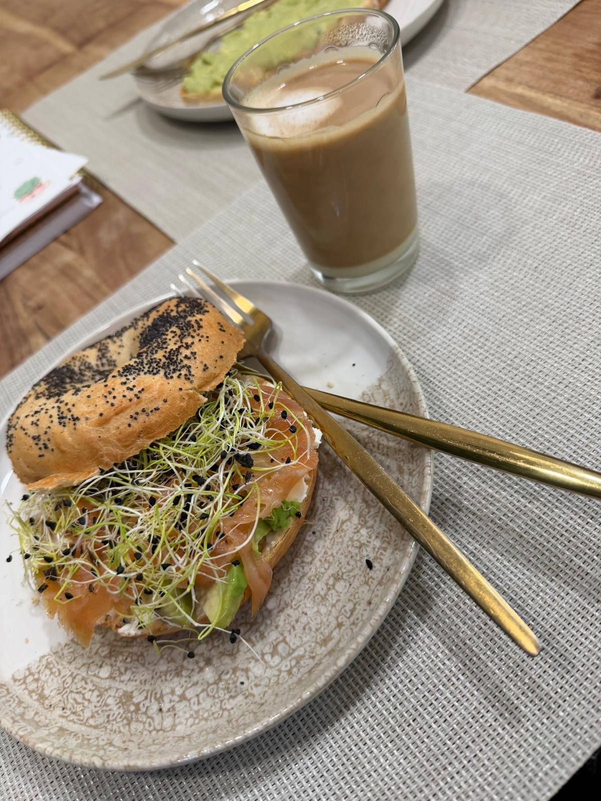 Brunch en Zaragoza: bagel de salmón ahumado con aguacate y brotes junto a un café con leche en Mediterránea Café